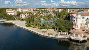A resort with a pool, palm trees, and a waterfront view. - Escape to Paradise: Your Family Adventure Awaits- Marriott's Grande Vista- 2 Bd (Orlando)