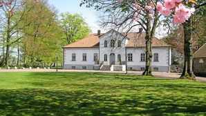 A large, white building with a red-tiled roof, surrounded by a well-maintained lawn and trees. - Nice home in Ekeby with WiFi (Ekeby)