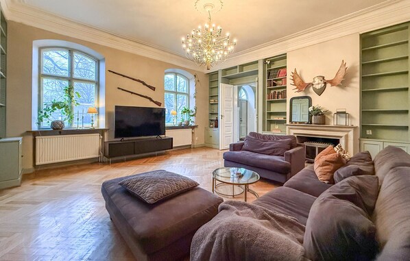 A living room with a television, sofas, a chandelier, and bookshelves.