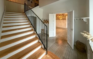 A wooden staircase with black railings leading to a room with white doors and a chandelier.