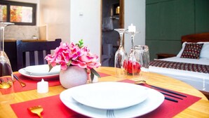 A neatly set dining table with plates, cutlery, and a vase of pink flowers. - Loft VIIM | Les Ferys du lac (Ouidah)