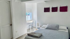 Un dormitorio con una cama, un escritorio y una silla. Hay toallas sobre la cama.