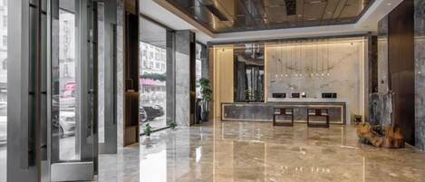 A modern lobby with a marble floor, a reception desk, and a large window.