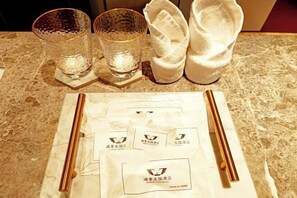A table with two glasses, a pair of chopsticks, and a napkin on a marble surface. - Hongye Youyi Hotel (Yongkang)