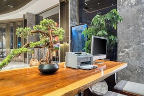 A reception desk with a bonsai tree, a flat-screen TV, and a printer. - Hongye Youyi Hotel (Yongkang)
