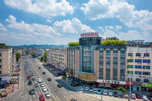 Un edificio moderno de varios pisos, con una llamativa fachada de vidrio y un jardín en la azotea.