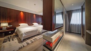 Een moderne hotelkamer met een groot bed, een flatscreen televisie, een open haard en een grote spiegel.