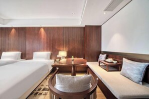 A hotel room with two beds, a sofa, a round table, and a lamp. - Hongye Youyi Hotel (Yongkang)