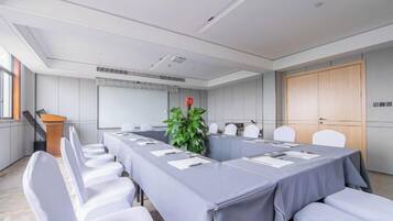 A conference room with a long table, chairs, a podium, and a plant.