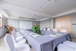 A conference room with a long table, chairs, a podium, and a plant. - Hongye Youyi Hotel (Yongkang)