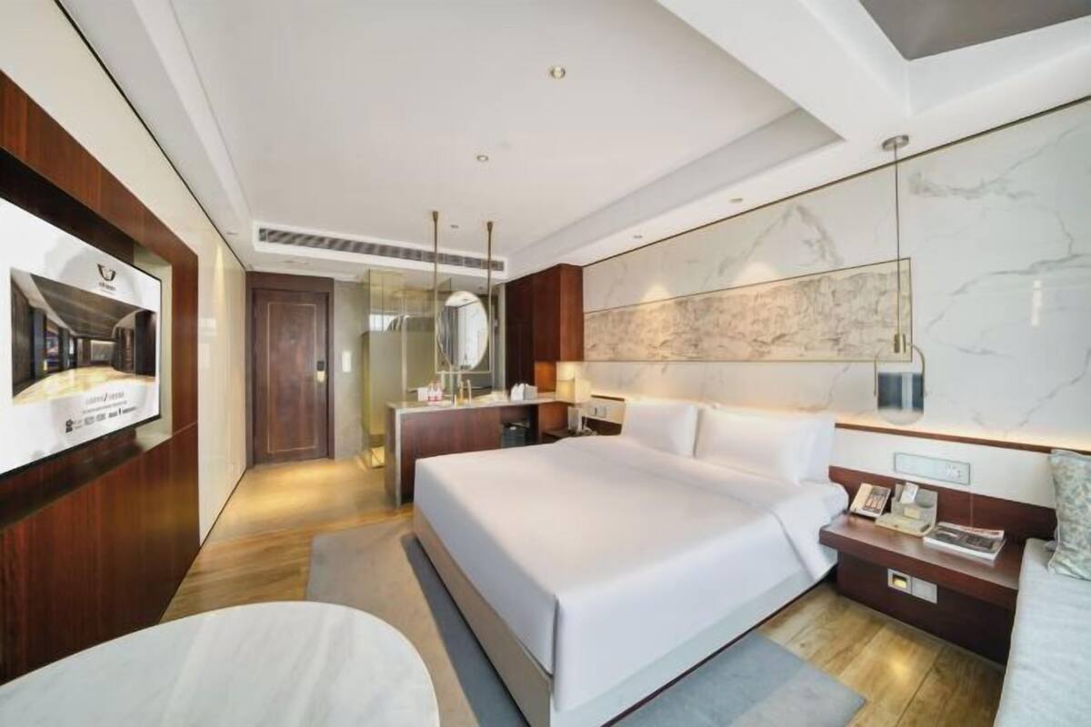 Ein modernes Hotelzimmer mit einem großen Bett, einem Schreibtisch, einem Spiegel und einer Karte an der Wand.