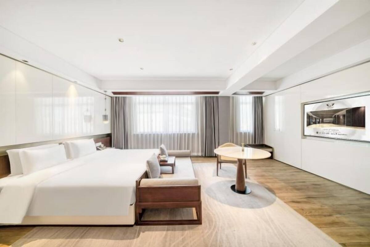 Ein modernes Hotelzimmer mit einem großen Bett, einem Schlafsofa, einem kleinen Tisch und einem Fernseher an der Wand.