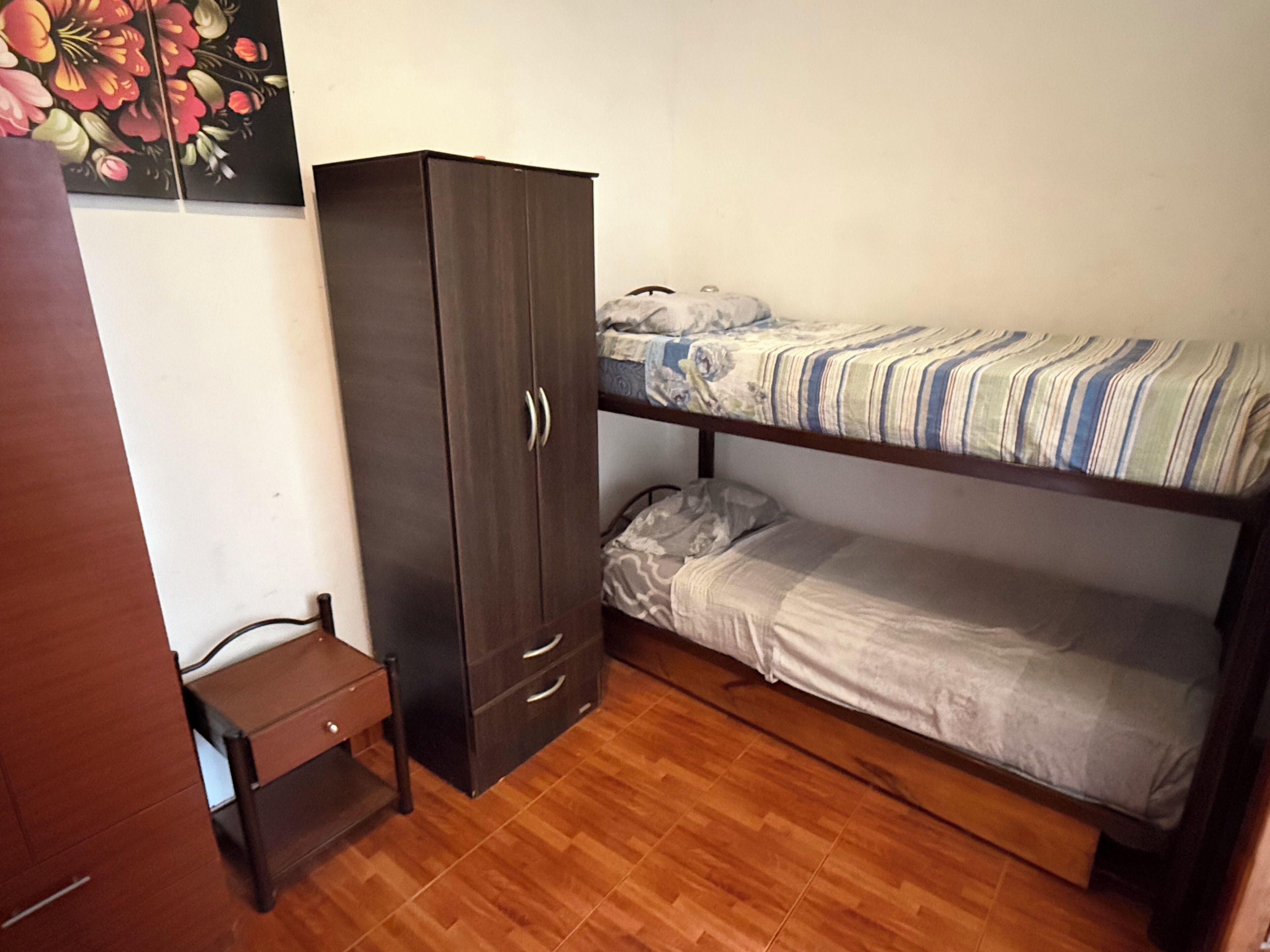 Un dormitorio pequeño con literas, un armario y una mesita.