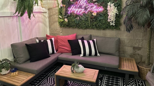A cozy seating area with a sofa, cushions, and a neon sign.