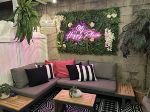 A cozy seating area with a sofa, cushions, and a neon sign. - Chateau de Manhattan Beach (Manhattan Beach)
