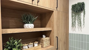 A wooden cabinet with shelves, a hanging plant, and a tiled wall.