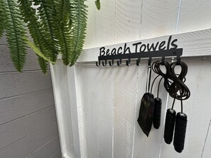 Un panneau fixé au mur, portant l’inscription « Serviettes de plage » et muni de crochets pour les serviettes.