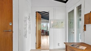 A hallway with a wooden door, a desk with a magazine, and a framed picture on the wall.
