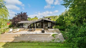 A wooden deck with outdoor seating and a staircase leading to a covered area with a table and chairs.