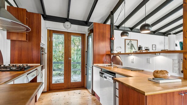 A modern kitchen with wooden cabinets, a stainless steel refrigerator, and a wooden countertop.