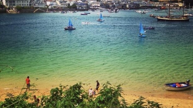 A coastal town with clear waters, boats, and a sandy beach.