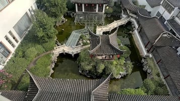 A traditional courtyard with tiled roofs, a central water feature, and a bridge connecting different sections.