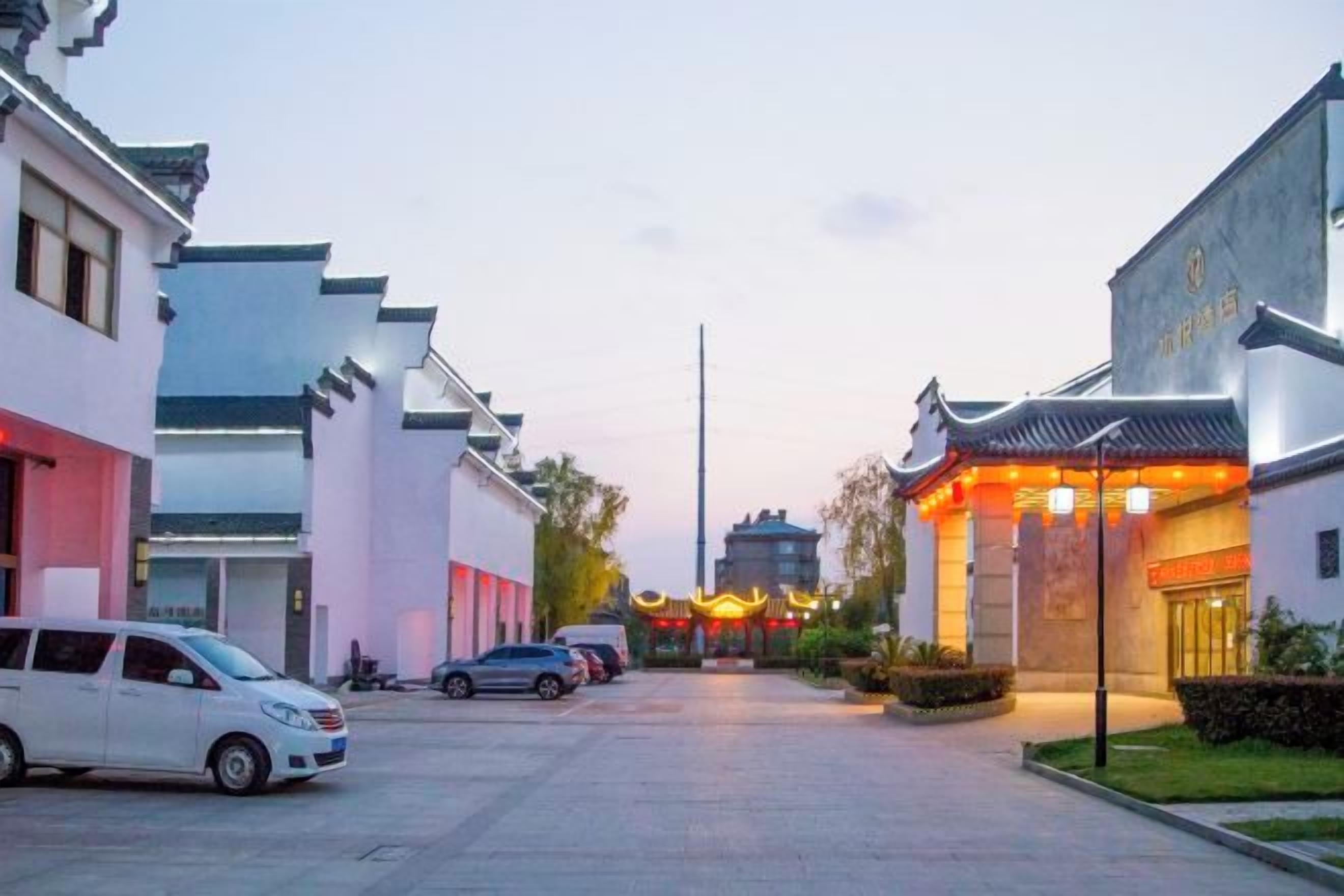 A traditional building with a modern entrance, parked cars, and a clear sky.