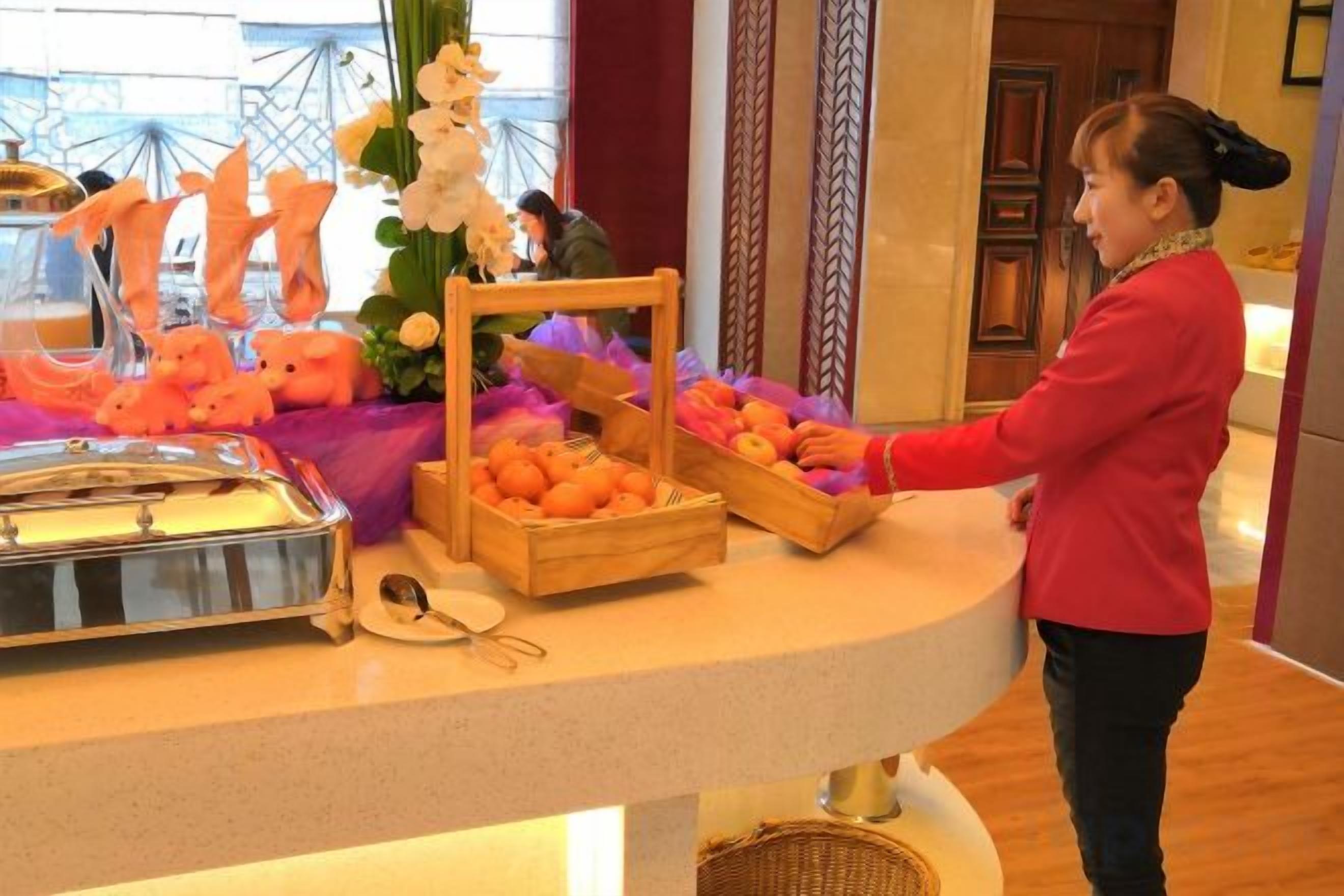 Montaje de bufé con diferentes alimentos y una persona sirviendo.