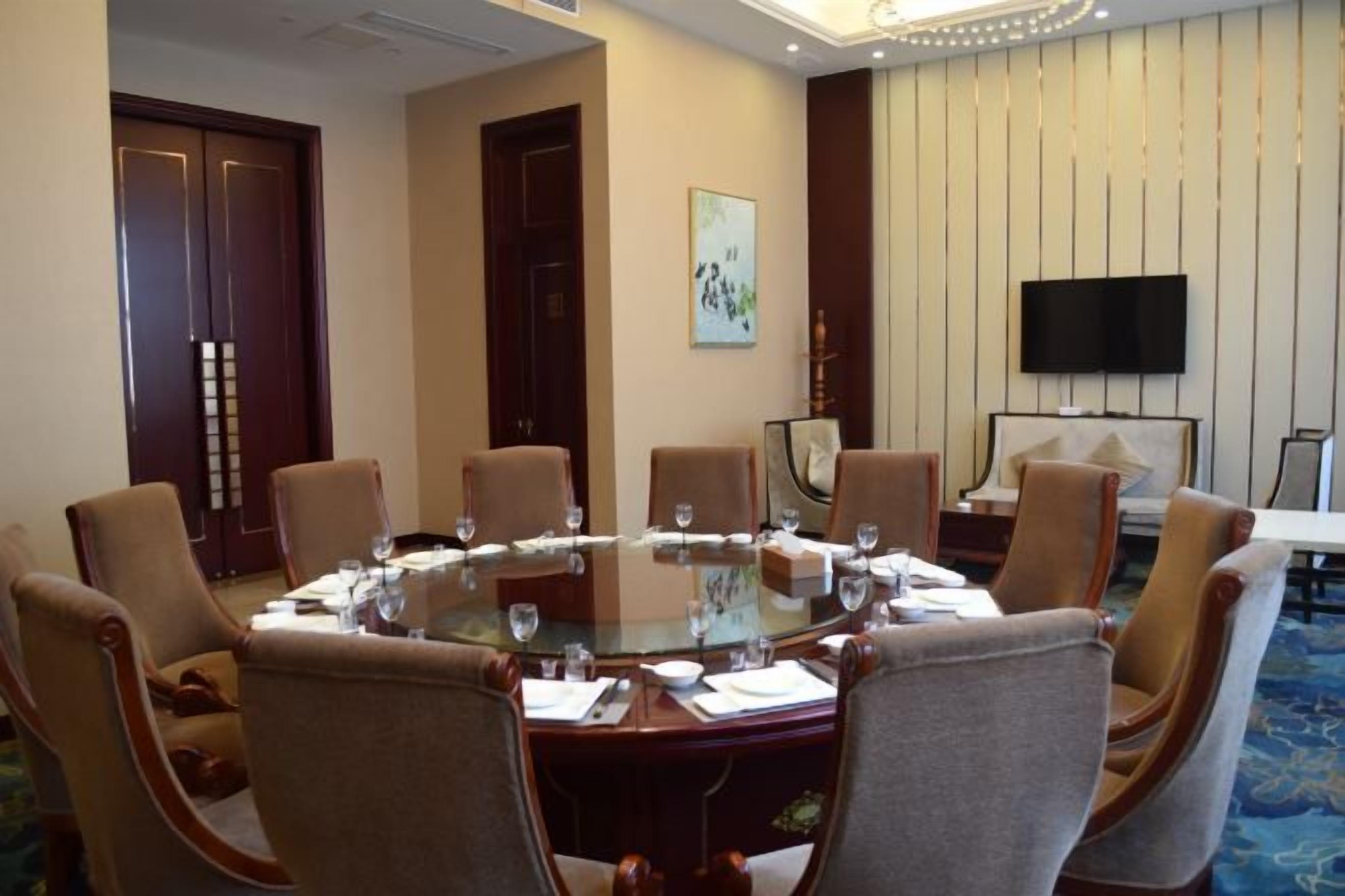 A conference room with a round table, chairs, and a television on the wall.