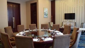 A conference room with a round table, chairs, and a television on the wall.