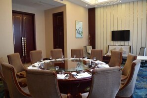 A conference room with a round table, chairs, and a television on the wall. - SuiningShuiyueHotel (Suining)