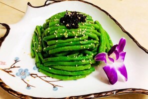A plate of green vegetable dish with a decorative flower. - SuiningShuiyueHotel (Suining)