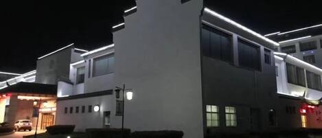 A modern building with a flat roof, large windows, and a parking area.