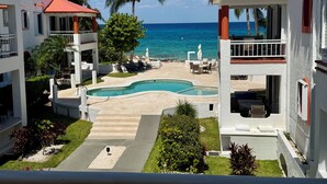 A resort with a pool, lounge chairs, and a view of the ocean.