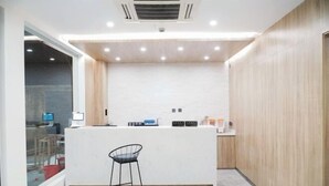 Una cocina moderna con encimera blanca, una silla negra y paneles de madera en las paredes.