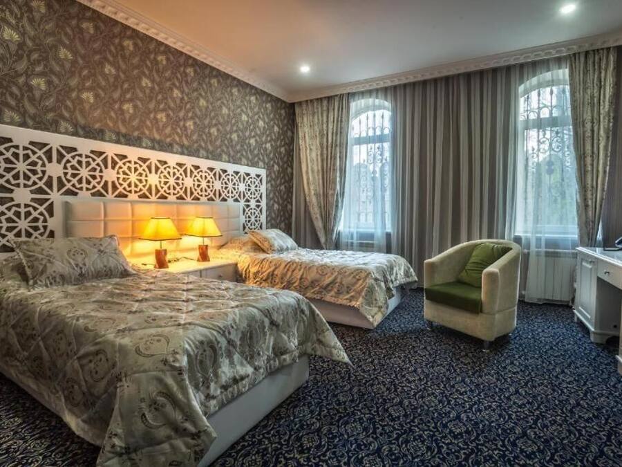 Ein Hotelzimmer mit zwei Betten, einem Schreibtisch, einem Stuhl und einer Wandverkleidung.