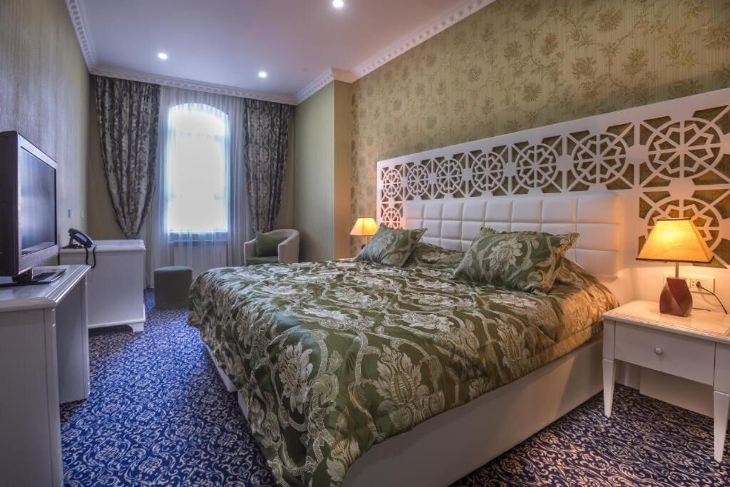 A hotel room with a large bed, a television, a desk, and a chair.