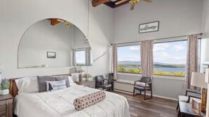 Une chambre avec un grand lit, un bureau, une chaise et une vue sur l’extérieur.