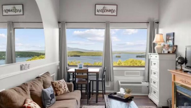 Une pièce avec vue sur un lac, comprenant un canapé, une table et une commode.