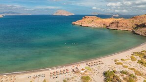 A beach with clear turquoise waters, rocky outcrops, and a sandy shore with umbrellas and sun loungers. - Two bedroom suite at Villa Del Palmar resort, Danzante Bay TPC golf course. (Ensenada)