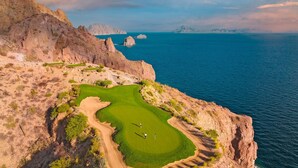 A coastal golf course with a winding path, a green, and a view of the sea and mountains. - Two bedroom suite at Villa Del Palmar resort, Danzante Bay TPC golf course. (Ensenada)