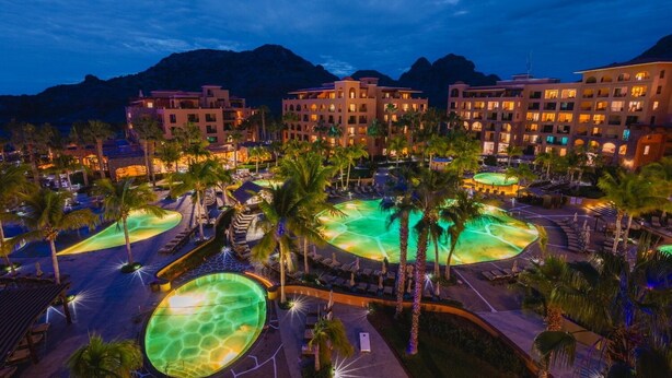 A resort with multiple swimming pools, palm trees, and buildings with balconies. - Two bedroom suite at Villa Del Palmar resort, Danzante Bay TPC golf course. (Ensenada)