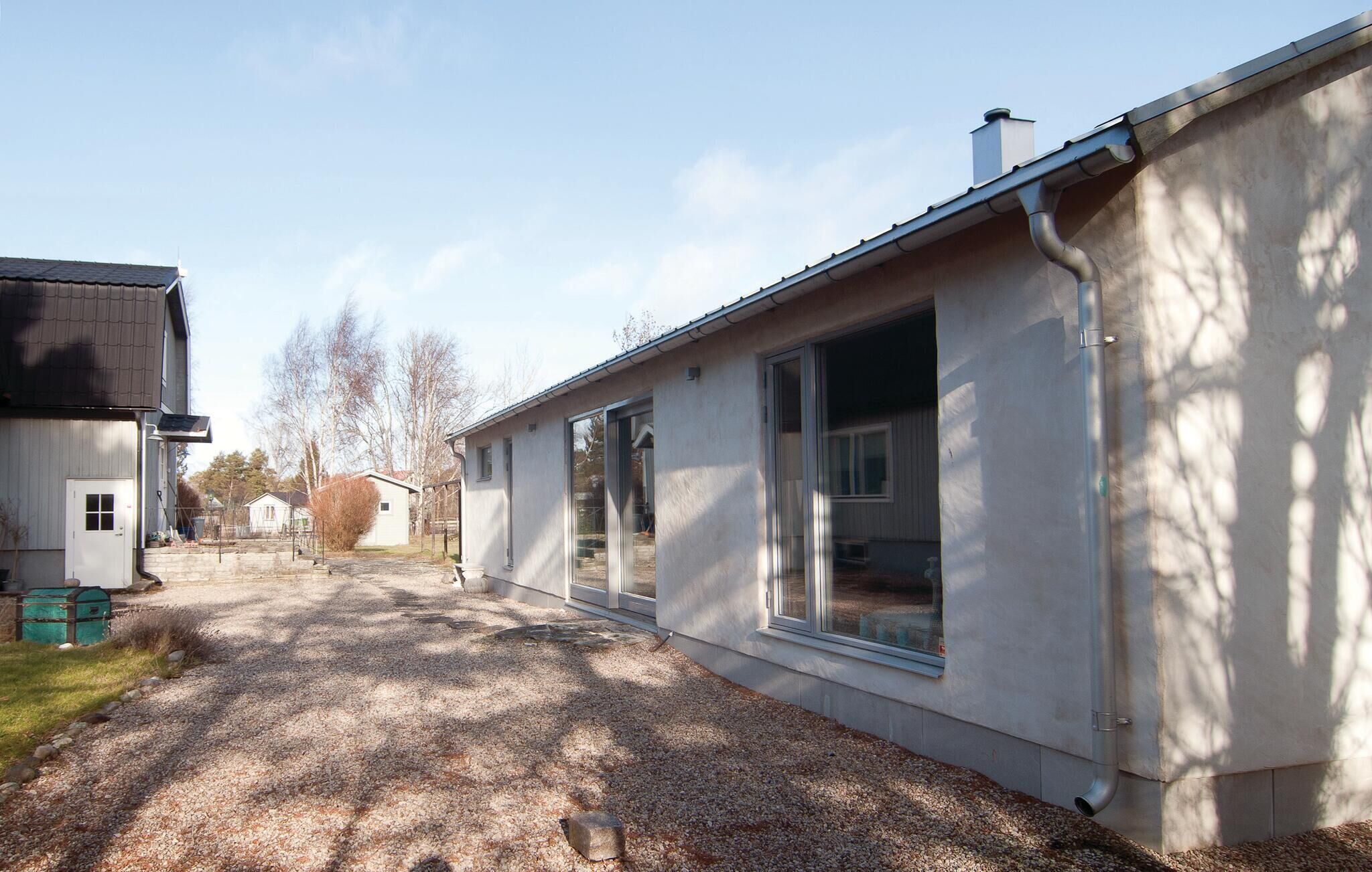 A residential building with a gravel driveway, large windows, and a metal roof.