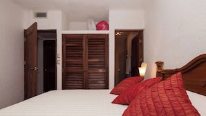 Ein Schlafzimmer mit einem Bett, roten Kissen, einem Holzschrank und einem Nachttisch mit Lampe.