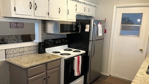 A kitchen with white cabinets, a black stove, and a stainless steel refrigerator. - AIMEE'S HEART OF MOORE (Moore)