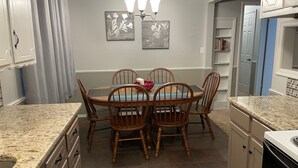 A dining area with a round table, four wooden chairs, a chandelier, and two wall-mounted paintings. - AIMEE'S HEART OF MOORE (Moore)