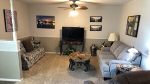 A living room with a sofa, armchair, coffee table, TV, and decorative items. - AIMEE'S HEART OF MOORE (Moore)