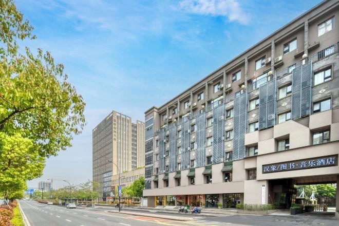Un hotel de varios pisos con fachada moderna, que combina elementos de vidrio y metal.