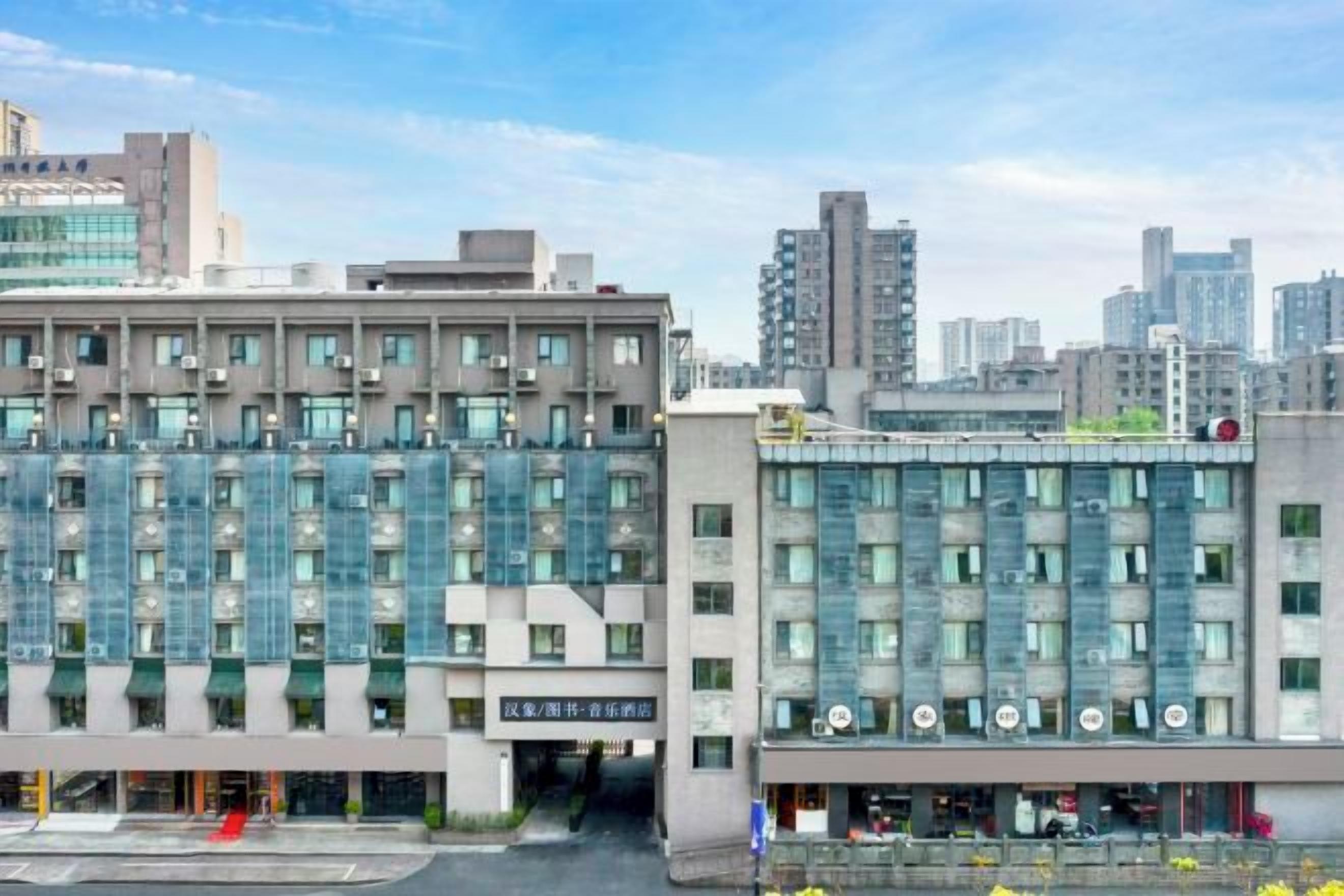 Un hotel moderno con fachada de vidrio, varios pisos y una entrada destacada.