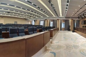 A conference room with rows of chairs, a long table, and a stage.